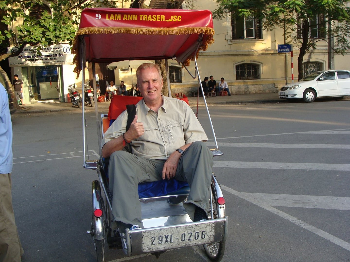 Ron smiling in a bright red cycle rickshaw in Hanoi in 2013