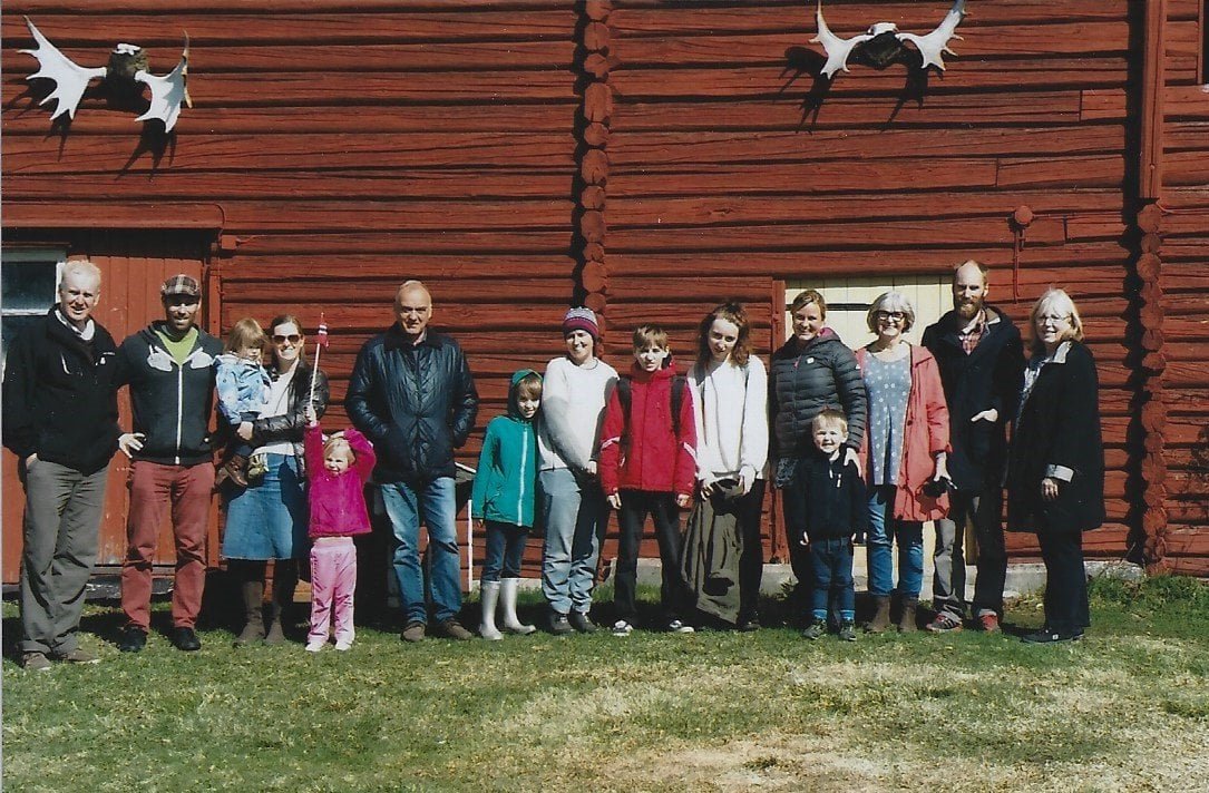 Family gathered in front of a red timber building in Norway